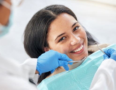 a smiling woman having her teeth examined by a dentist