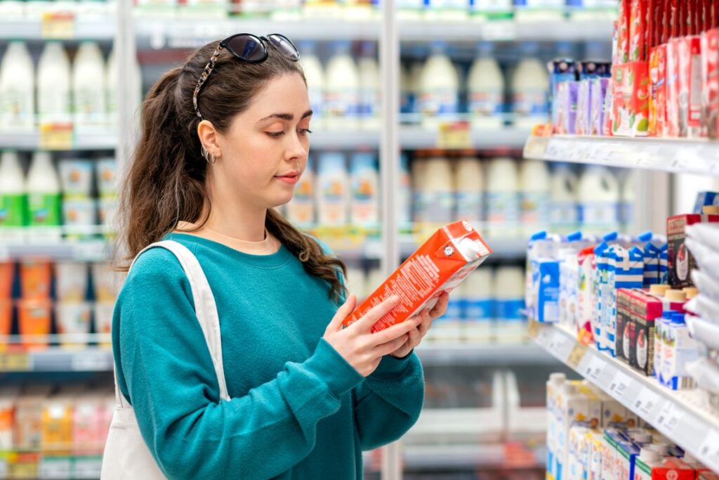 A woman reading the label on a food item at the grocery store.