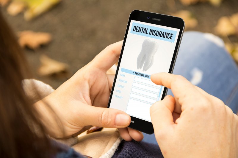 A woman using her phone to check her dental insurance details